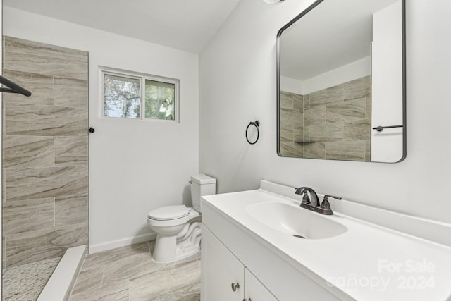 bathroom with a tile shower, vanity, and toilet