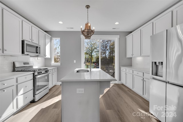 kitchen featuring white cabinetry, sink, tasteful backsplash, a kitchen island with sink, and appliances with stainless steel finishes