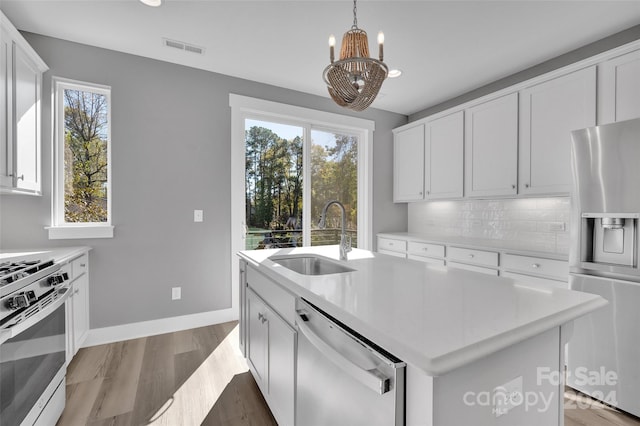 kitchen featuring white cabinetry, sink, stainless steel appliances, dark hardwood / wood-style floors, and a center island with sink