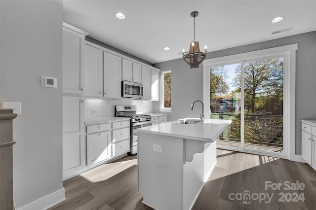 kitchen featuring dark hardwood / wood-style flooring, stainless steel appliances, sink, white cabinets, and an island with sink