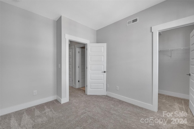 unfurnished bedroom with light carpet and a closet