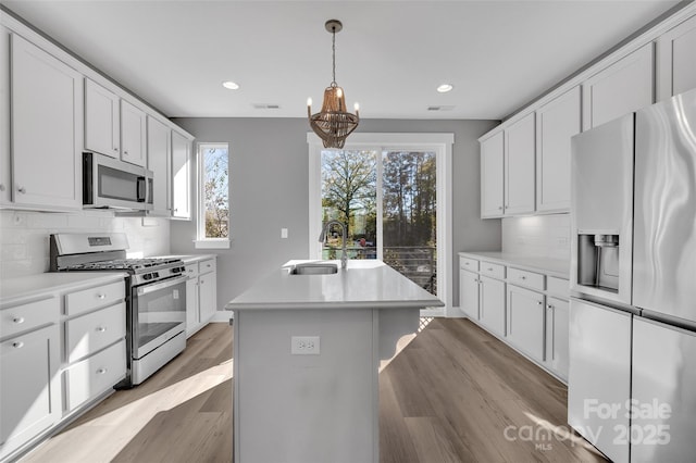 kitchen with visible vents, an inviting chandelier, a sink, appliances with stainless steel finishes, and an island with sink