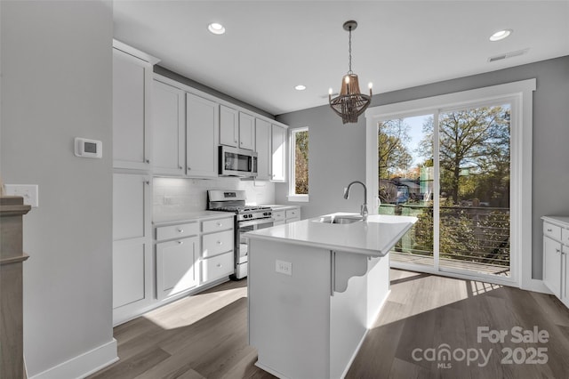 kitchen with dark wood-style flooring, a chandelier, visible vents, stainless steel appliances, and a sink
