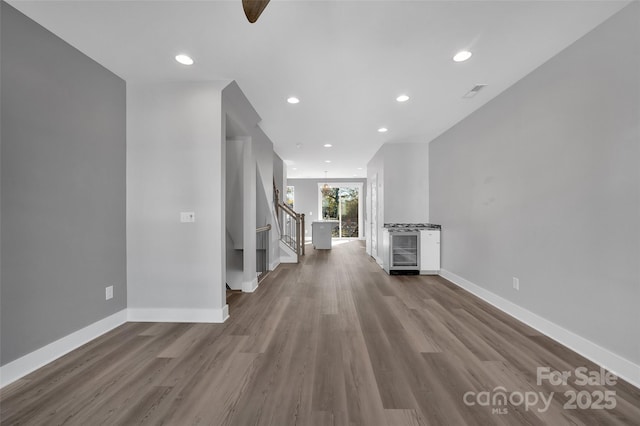 unfurnished living room with wood finished floors, baseboards, and recessed lighting