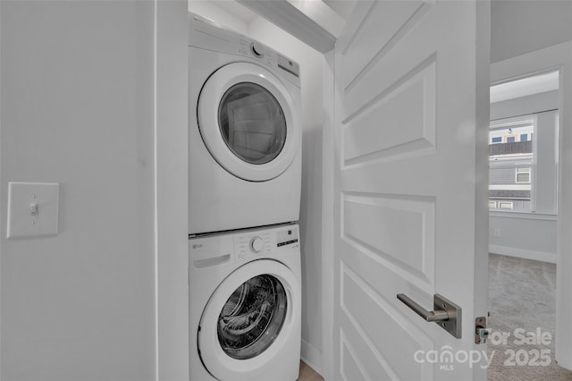 washroom featuring carpet, stacked washer / dryer, laundry area, and baseboards