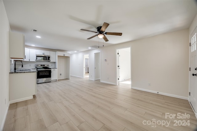 unfurnished living room featuring light wood-type flooring, ceiling fan, and sink