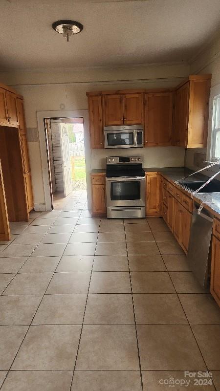 kitchen featuring appliances with stainless steel finishes, light tile patterned floors, and a wealth of natural light