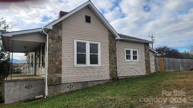 view of side of property featuring a lawn and covered porch