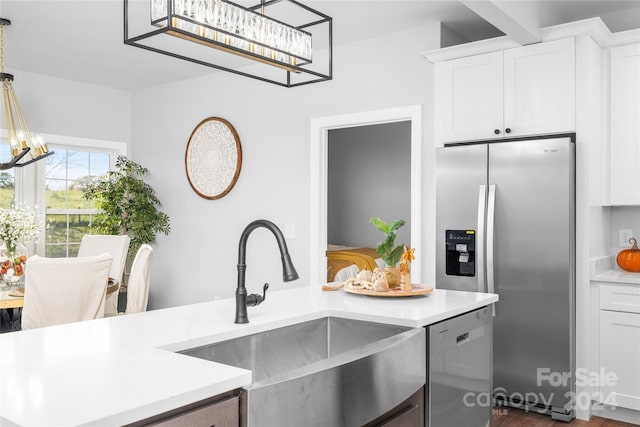 kitchen with white cabinets, appliances with stainless steel finishes, pendant lighting, and sink