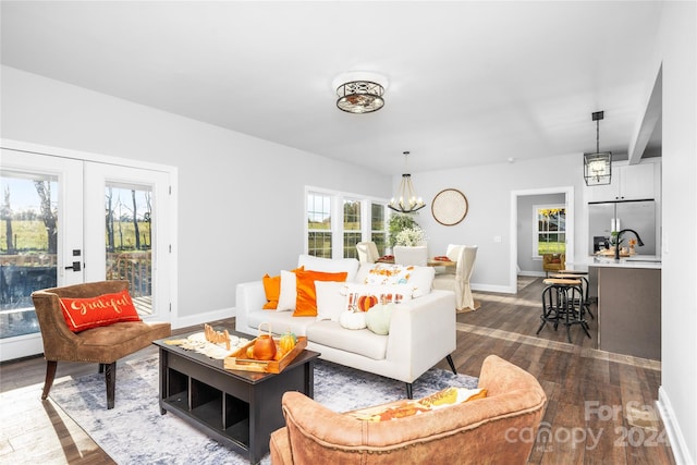 living room featuring a notable chandelier, dark hardwood / wood-style floors, and french doors