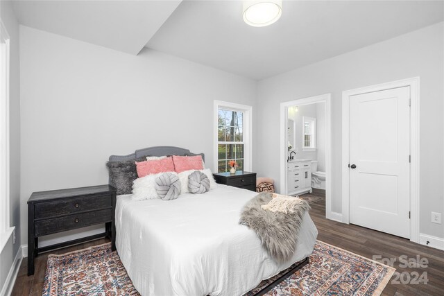 bedroom featuring dark wood-type flooring and ensuite bath