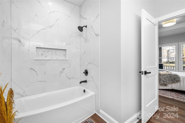 bathroom with hardwood / wood-style flooring and tiled shower / bath