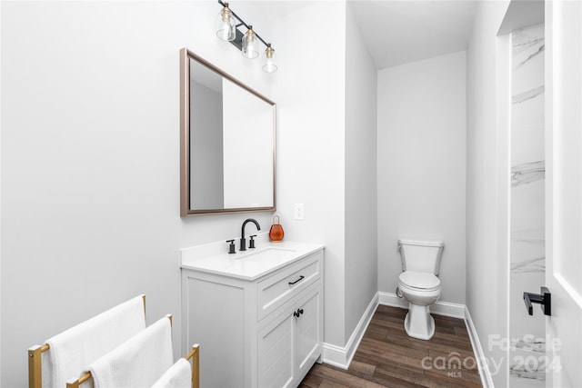 bathroom with hardwood / wood-style flooring, vanity, and toilet