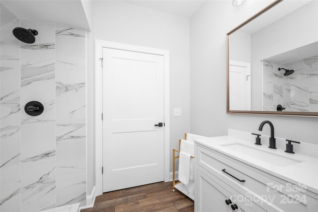 bathroom featuring hardwood / wood-style floors, vanity, and a tile shower