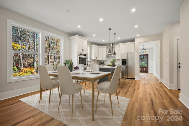 dining space with light wood-type flooring and sink