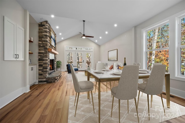 dining area with a fireplace, a healthy amount of sunlight, lofted ceiling, and light wood-type flooring