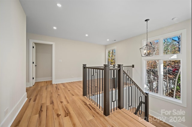 hall with light wood-type flooring and a notable chandelier