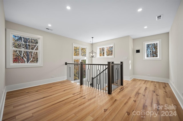 hallway with a chandelier, light hardwood / wood-style floors, and a healthy amount of sunlight