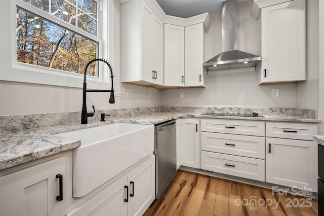 kitchen featuring a sink, white cabinetry, wall chimney exhaust hood, light wood finished floors, and dishwasher