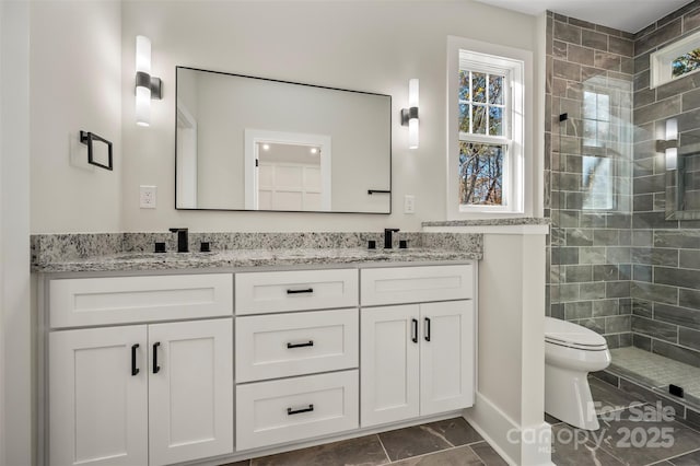 bathroom with double vanity, toilet, a tile shower, and a sink