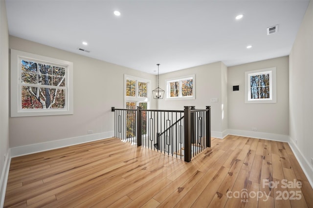 corridor featuring an upstairs landing, visible vents, light wood finished floors, and baseboards