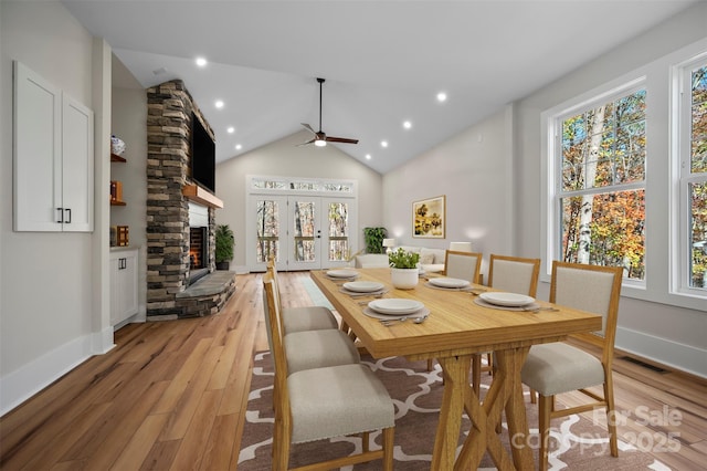 492 Mountain View Dr, Columbus, NC 28722 - dining room with light wood-style floors, a ceiling fan, a stone fireplace, high vaulted ceiling, and french doors
