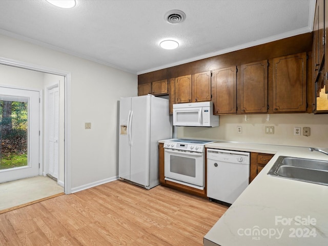 kitchen featuring light wood-type flooring, white appliances, sink, and ornamental molding