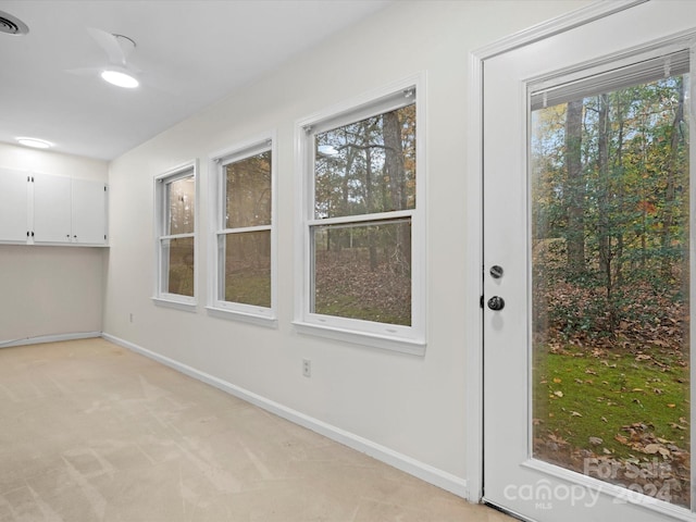 doorway to outside featuring light carpet and plenty of natural light