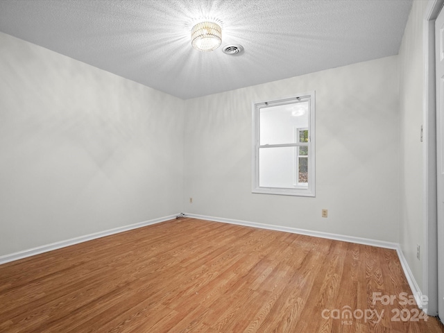 empty room with hardwood / wood-style flooring and a textured ceiling