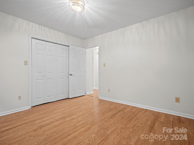 unfurnished bedroom with a textured ceiling, light hardwood / wood-style flooring, and a closet