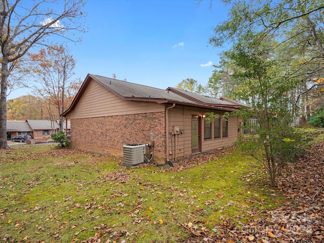 view of side of home featuring a lawn and central air condition unit