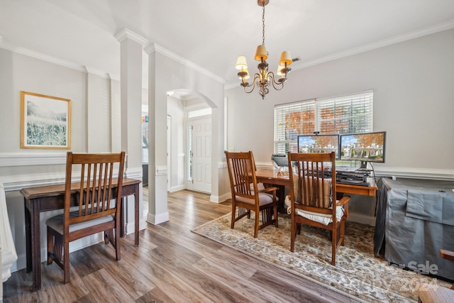 dining space featuring wood-type flooring, an inviting chandelier, and crown molding