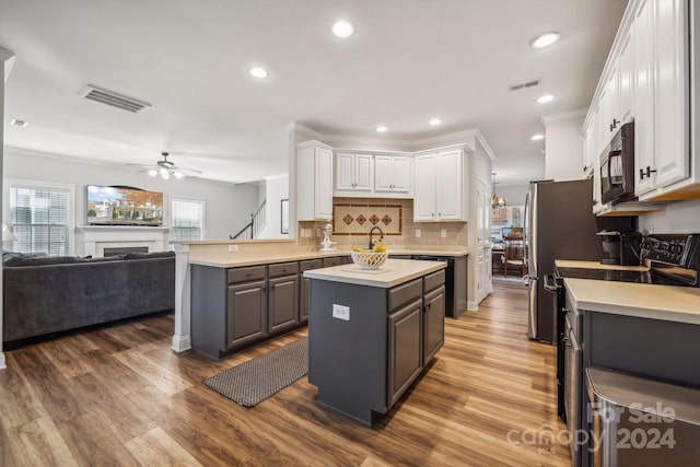 kitchen with ceiling fan, black appliances, white cabinets, hardwood / wood-style floors, and a kitchen island