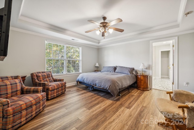 bedroom with light hardwood / wood-style flooring, a raised ceiling, ceiling fan, and ornamental molding