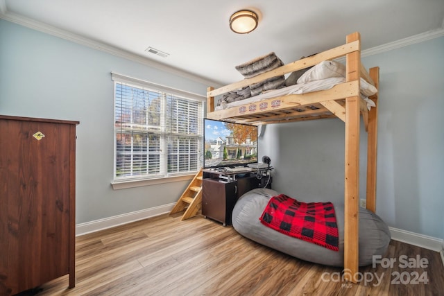 bedroom with light hardwood / wood-style flooring and crown molding