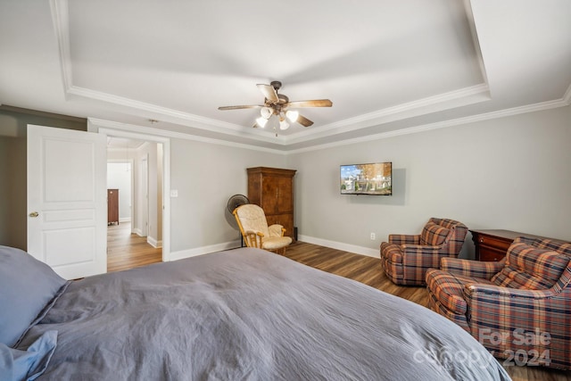 bedroom featuring a tray ceiling, ceiling fan, wood-type flooring, and ornamental molding