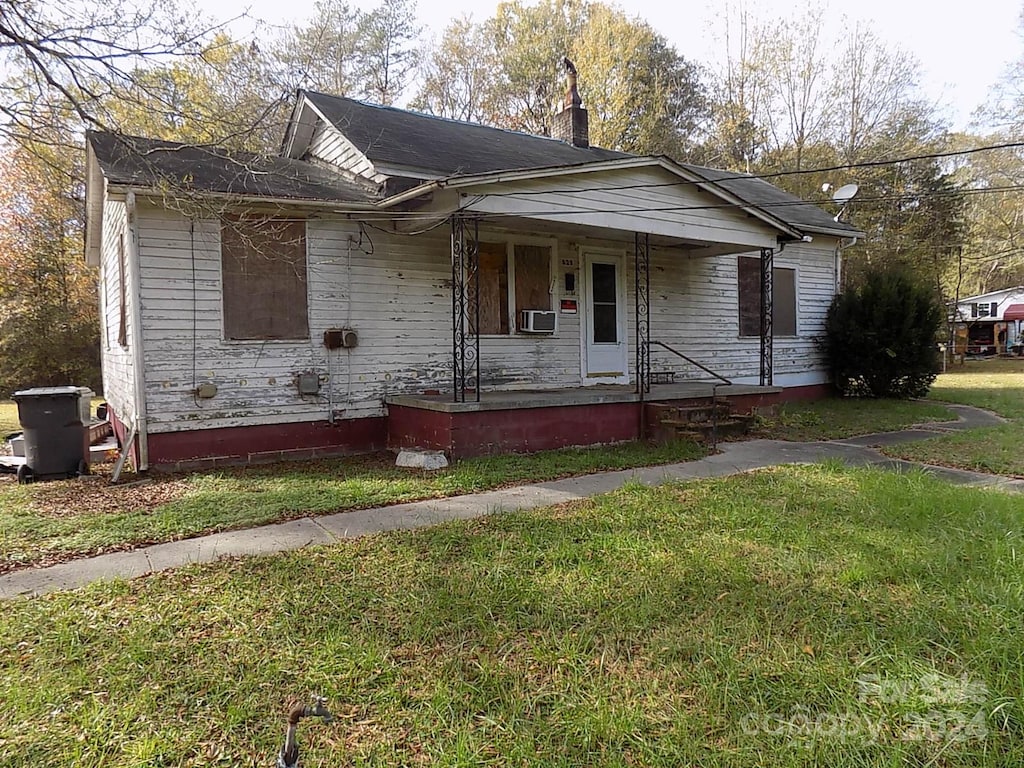 bungalow-style home featuring covered porch and a front lawn