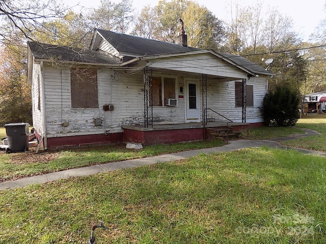 bungalow-style home featuring covered porch and a front lawn