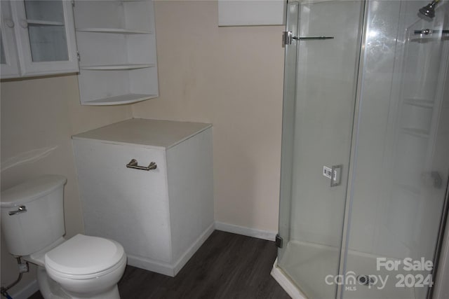 bathroom with hardwood / wood-style floors, a shower with shower door, and toilet