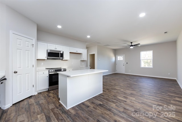 kitchen featuring dark wood-type flooring, ceiling fan, a kitchen island, white cabinetry, and stainless steel appliances