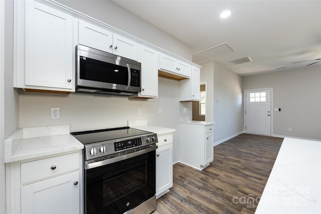 kitchen with appliances with stainless steel finishes, white cabinetry, dark wood-type flooring, and light stone counters