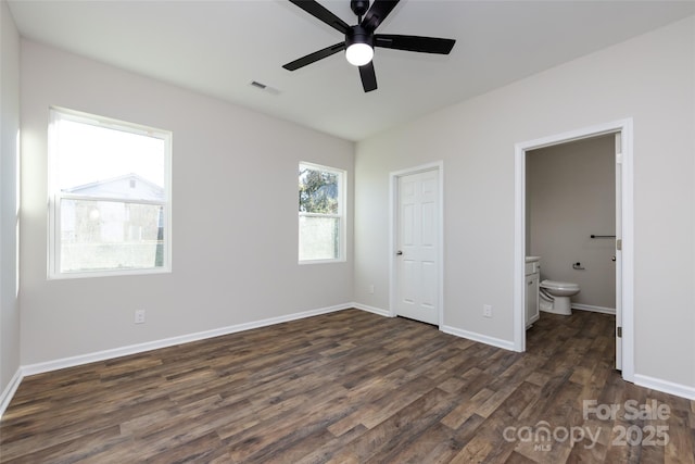 unfurnished bedroom featuring ceiling fan, dark hardwood / wood-style flooring, ensuite bathroom, and a closet