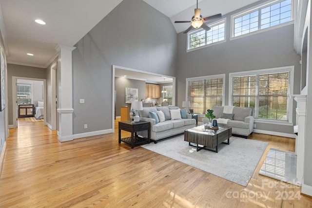 living room featuring a high ceiling, light hardwood / wood-style flooring, ceiling fan, and crown molding