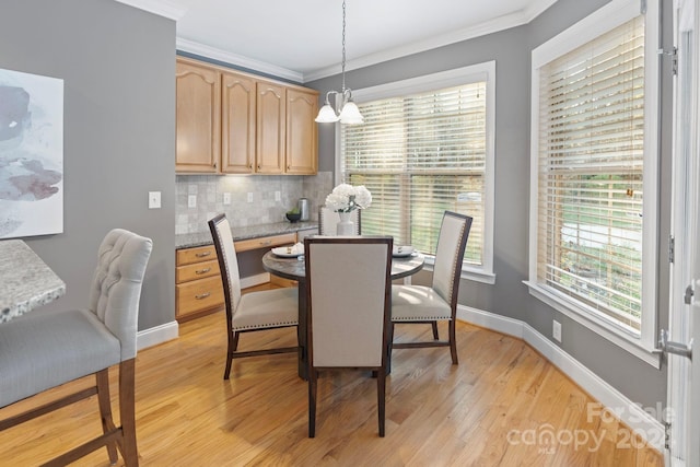 dining space featuring an inviting chandelier, ornamental molding, and light hardwood / wood-style flooring