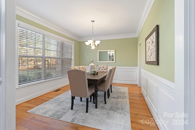 dining area featuring a notable chandelier, ornamental molding, and light hardwood / wood-style flooring