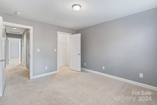 unfurnished bedroom featuring light colored carpet, a spacious closet, and a closet