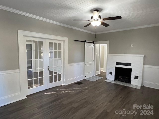 unfurnished living room with a fireplace, dark hardwood / wood-style flooring, a barn door, and ceiling fan