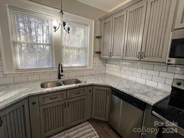 kitchen with appliances with stainless steel finishes, gray cabinets, pendant lighting, and sink