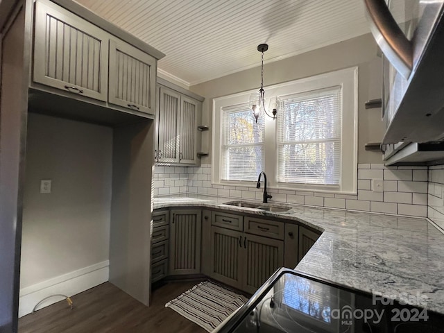 kitchen with decorative backsplash, light stone counters, crown molding, dark wood-type flooring, and sink