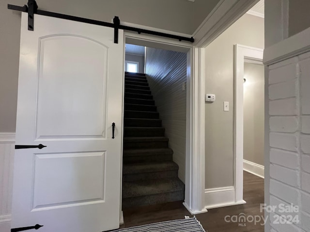 stairs featuring a barn door, hardwood / wood-style flooring, and ornamental molding